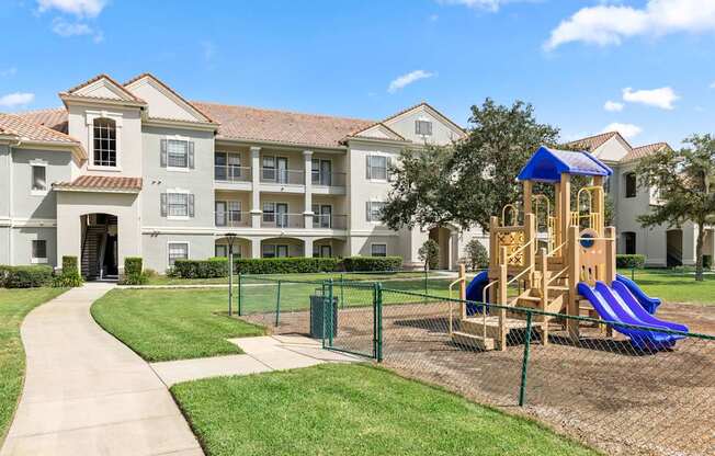 A playground with a blue slide is in front of a building.