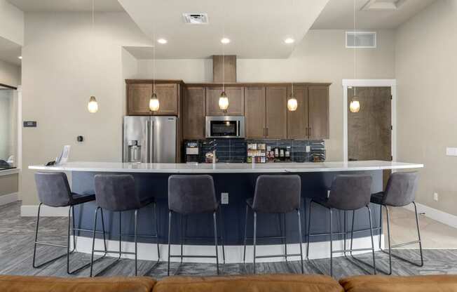 a kitchen with an island and bar with chairs and a refrigerator and