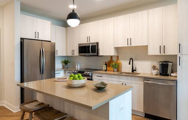 a kitchen with white cabinets and a large island with a bowl of fruit on it  at Century West Pryor, Missouri