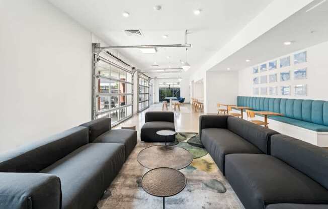 A modern living room with black leather sofas and a glass wall.