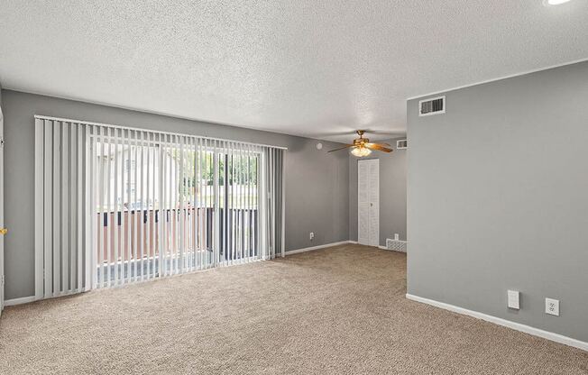 an empty living room with blinds and a ceiling fan