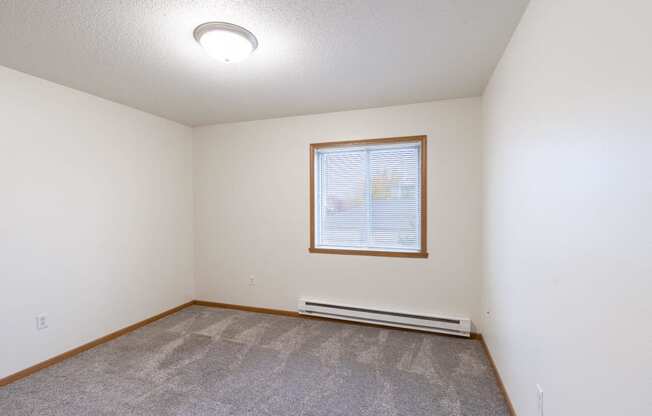 an empty living room with carpet and a window. Fargo, ND Oxford Apartments