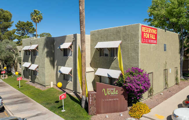 A building with a sign that says "RESERVING FOR FALL 2012-2013" is surrounded by palm trees.