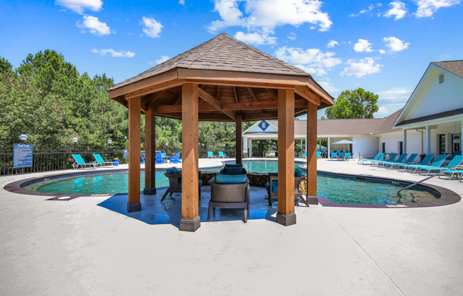 a gazebo with a grill next to a pool