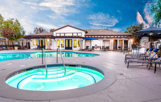 Three Bedroom apartments in Rancho Cucamonga CA - Barrington Place - Pool with Lounge Chairs, Tables with Chairs, Umbrellas, Spa, and View of Clubhouse in the Background