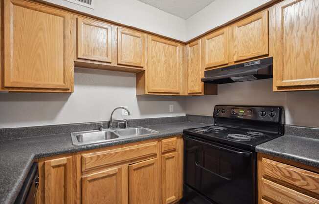 an empty kitchen with wood cabinets and black appliances