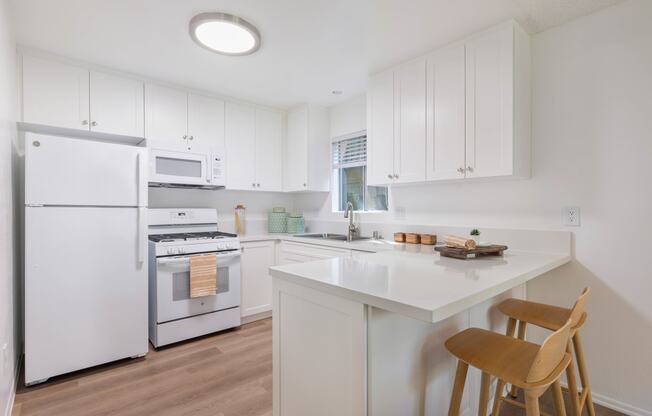 a kitchen with white cabinets and white appliances and a white counter top