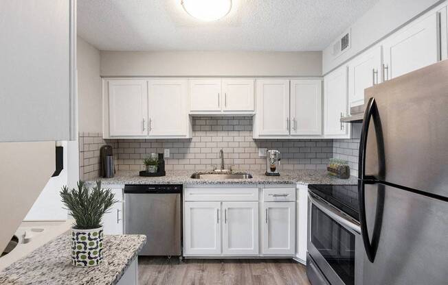 A kitchen with a black refrigerator and white cabinets.