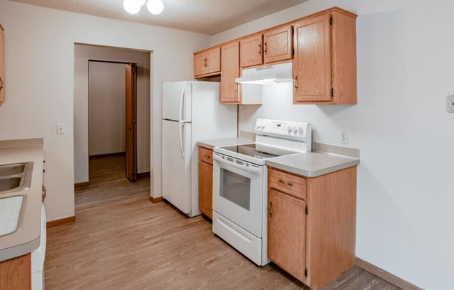 an empty kitchen with white appliances and wooden cabinets