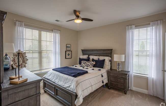 a bedroom with a bed and two windows and a ceiling fan