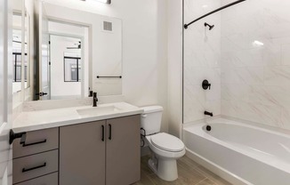 A white bathroom with a toilet, sink, and bathtub.