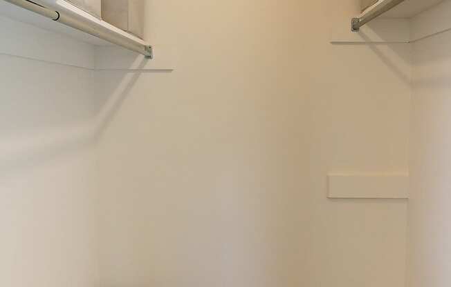 A walk in closet with a striped basket on the floor.