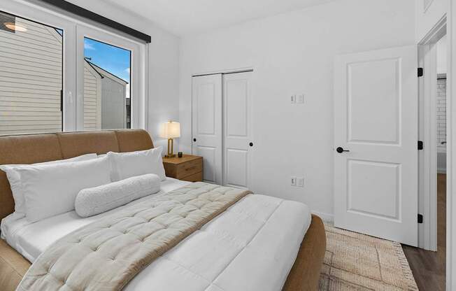 A bedroom with a large bed and a window with blinds.