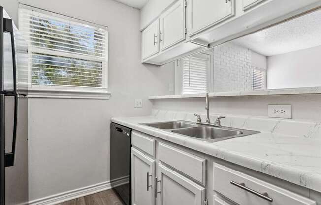 A kitchen with white cabinets and a black refrigerator.