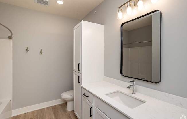 A white bathroom with a sink, mirror, and toilet.