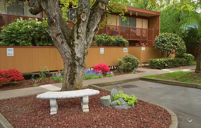 a stone bench sitting under a tree in front of a building