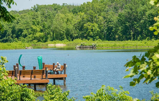 A wooden dock with two people sitting on it.