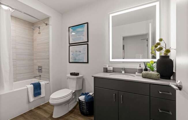 A bathroom with a white toilet, a white sink, and a white bathtub with a blue towel.