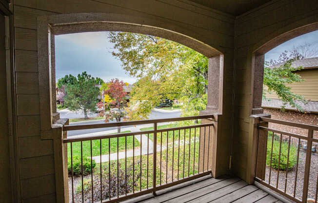 A view from a porch looking out to a street lined with trees.