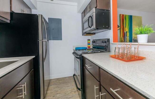 A kitchen with a black fridge, microwave, and stove.