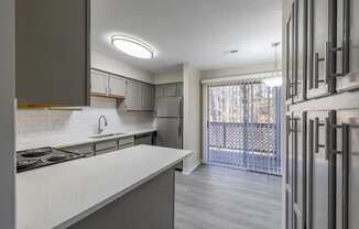 an empty kitchen with a sliding glass door to a balcony