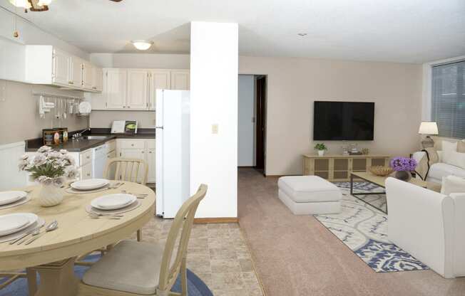 a living room with a table and chairs and a kitchen in the background