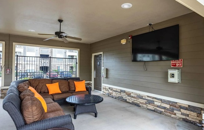 A living room with a black sofa and a television on the wall.