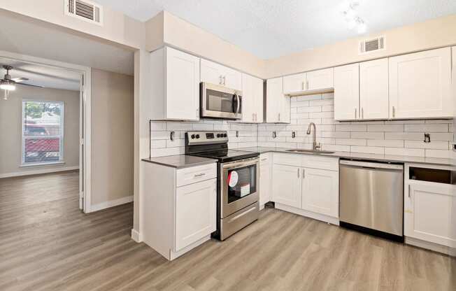 an empty kitchen with white cabinets and stainless steel appliances