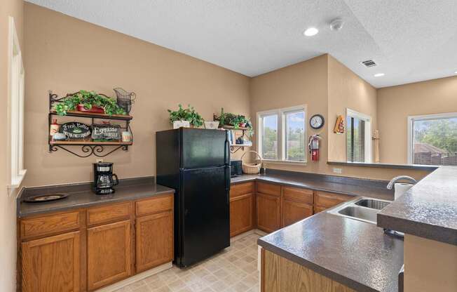 A kitchen with a black refrigerator and wooden cabinets.