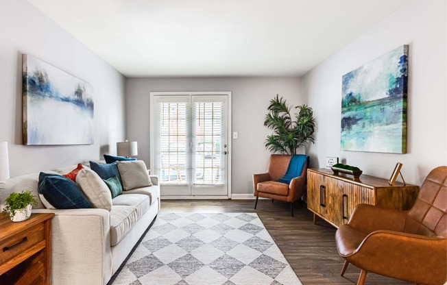a living room with a couch and chairs and a door to a balcony