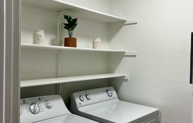 a white washer and dryer in a laundry room with shelves