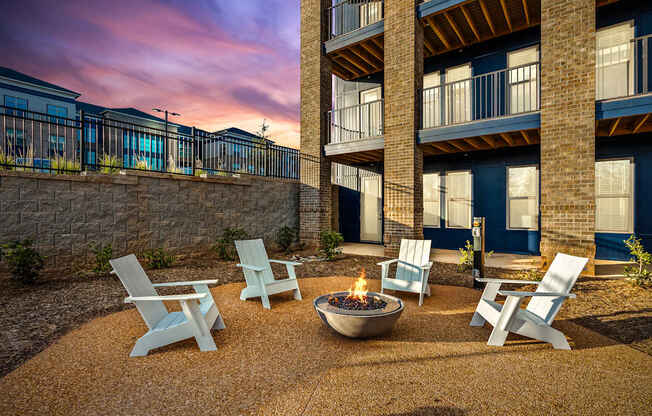 A fire pit sits in the middle of a gravel patio surrounded by four chairs