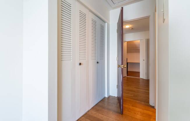 a hallway with white shutters and wood floors