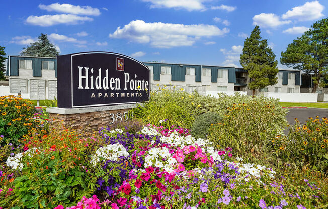 a sign apartments in front of a garden of flowers