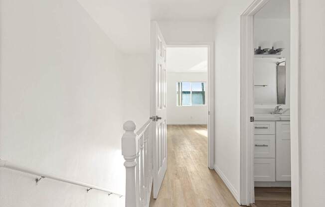 A white hallway leads to a kitchen.