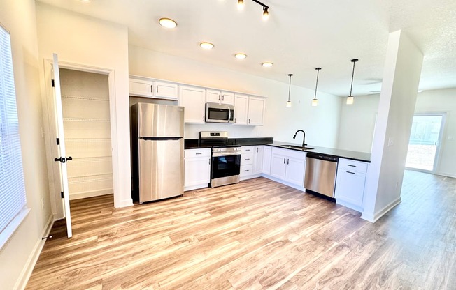 A kitchen with wooden floors and white cabinets.