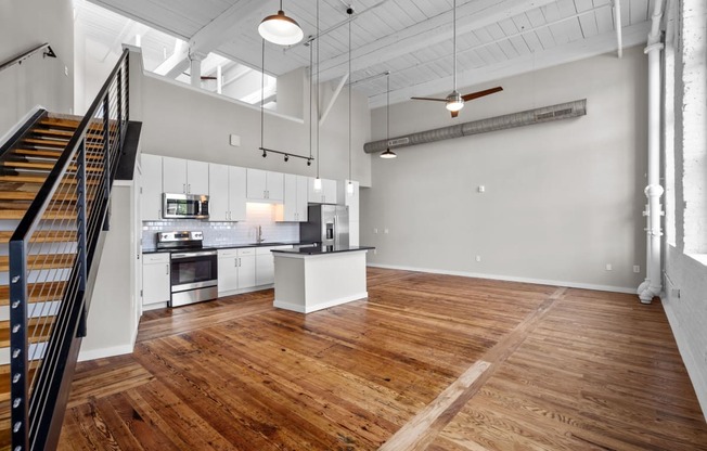 an open living room with a kitchen and a staircase at Spinning Mill Lofts, Clayton, NC 27520