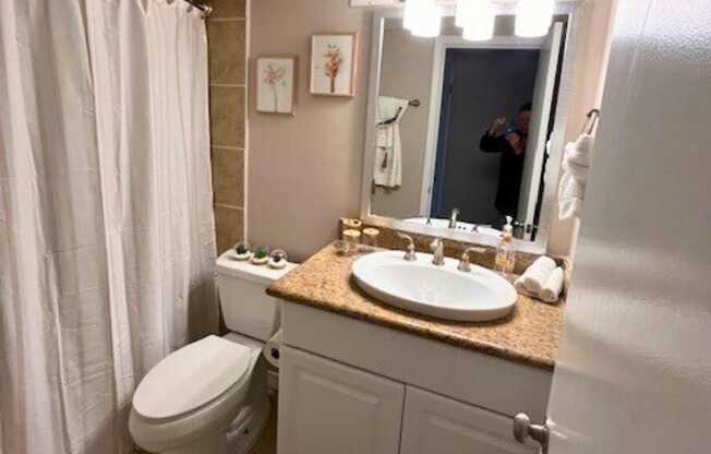 A bathroom with a toilet, sink, and mirror.