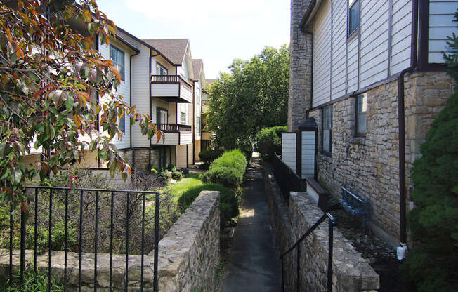 A narrow alley with a metal fence on the left and a stone wall on the right.