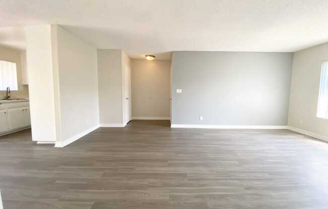 an empty living room with wood flooring and white walls