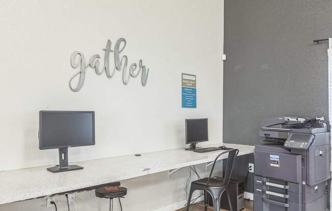A white desk with a computer monitor and a printer on it.