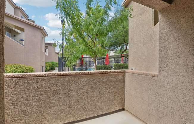 A wall with a window and a tree in the background.