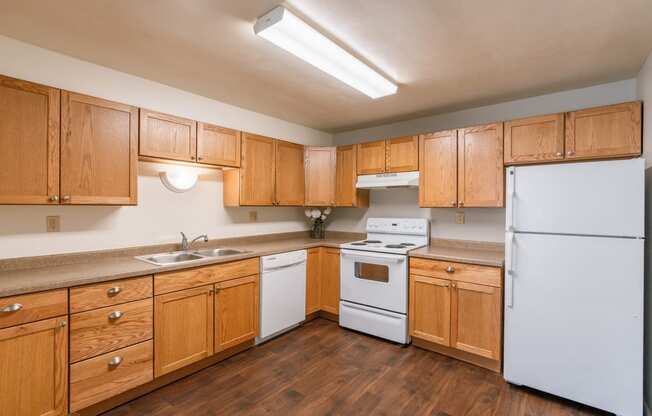 a kitchen with white appliances and wooden cabinets. Fargo, ND Spring Apartments