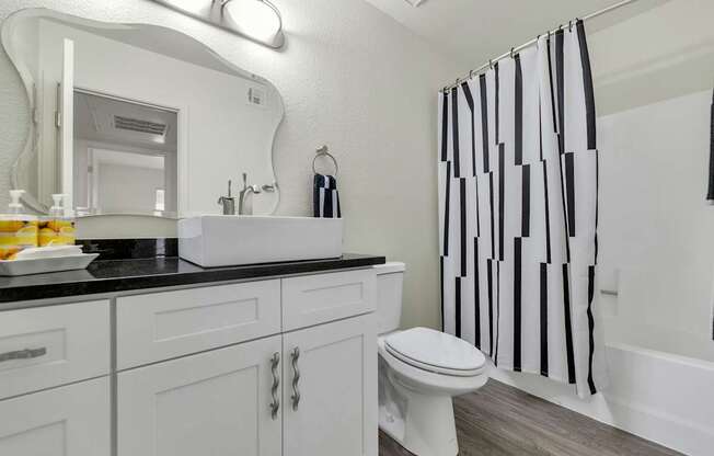 A white toilet sits next to a sink in a bathroom at Urban WalkApartments on 6th Avenue, Phoenix, AZ