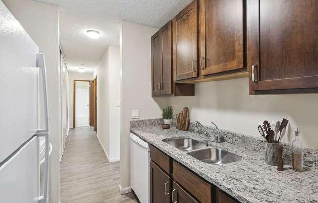 an empty kitchen with wood cabinets and a white refrigerator and sink