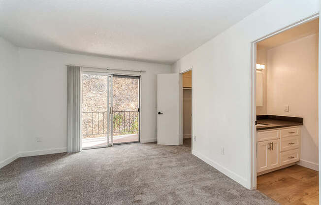 Model Bedroom with Carpet and attached Bathroom at Palmilla Apartments located in San Diego, CA.