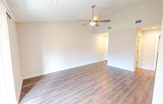 A room with a ceiling fan and wooden flooring.
