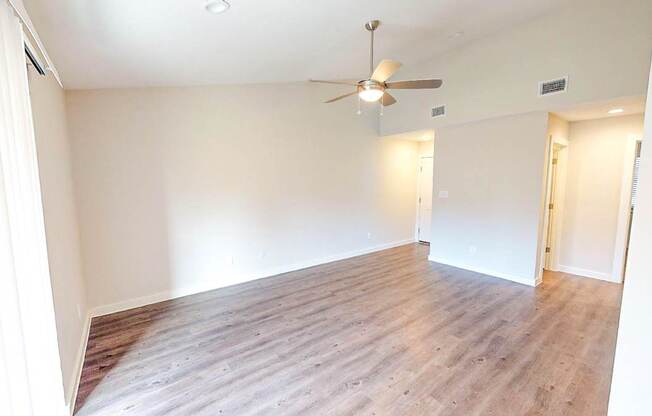 A room with a ceiling fan and wooden flooring.
