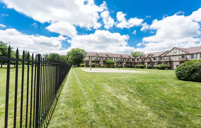 the view of an apartment building from a yard with a black fence