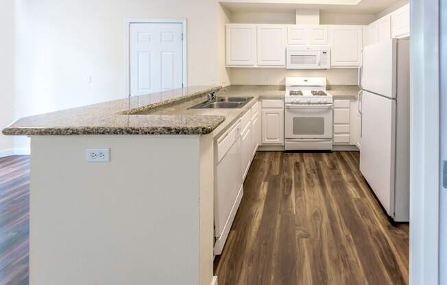 a kitchen with white appliances and a granite counter top